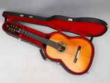 une guitare dans un étui, posée sur une surface blanche