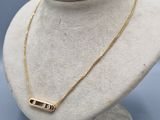 a gold plated necklace with a bar on a mannequin neck