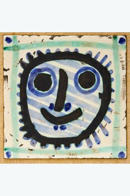 un carreau bleu et blanc sur lequel est représenté un visage souriant