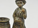a bronze figurine of a boy with a dog and a jar