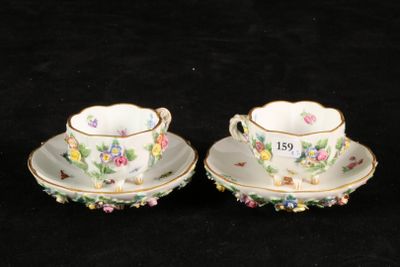 two cups and saucers with floral designs on them on a black background