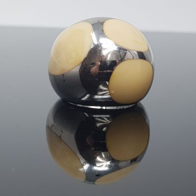 une boule argentée parsemée de points jaunes sur un fond noir