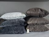 several pillows are stacked on top of each other on a shelf