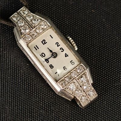 une montre en argent sertie de diamants, posée sur un fond noir