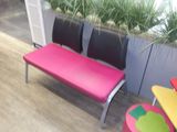 un banc rose avec deux chaises noires à côté d'une jardinière