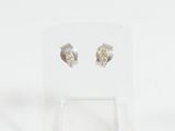 une paire de boucles d'oreilles en argent posée sur un présentoir transparent