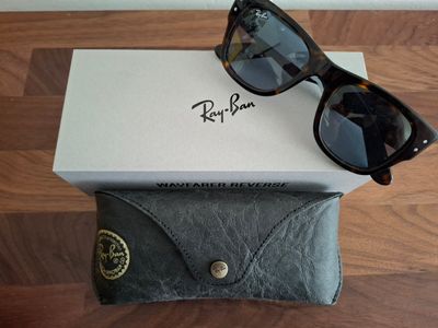 des lunettes de soleil Ray-Ban dans un étui posé sur une table en bois