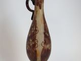 a brown and white vase with a black handle