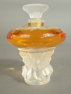 une petite bouteille en verre avec un bouchon doré, posée sur une table