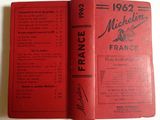 an old book with a red cover sitting on top of a table