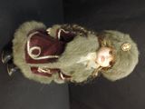 a doll that is wearing a fur coat and a hat