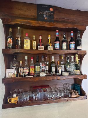 une étagère en bois sur laquelle sont posées de nombreuses bouteilles et verres
