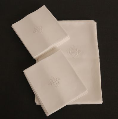 trois serviettes blanches ornées de monogrammes, posées sur une table