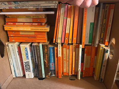 une boîte remplie de livres et une main qui tend la main vers un livre