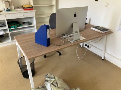 un bureau sur lequel se trouvent deux ordinateurs et un sac posé par terre