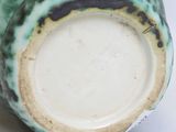 a close up of a green vase on a white surface