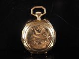 an image of a gold pocket watch sitting on a black surface