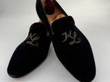 chaussons en velours noir ornés de monogrammes dorés sur la pointe