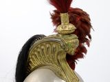 a helmet on a mannequin with a red feather on top