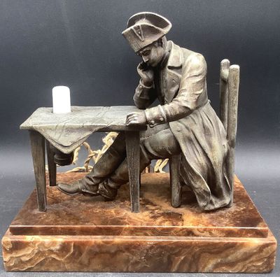 statue of a man sitting at a table with a candle in his hand