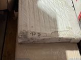 Des cartons contenant des matelas sont empilés les uns sur les autres dans un entrepôt