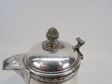 a silver tea pot with a lid on a white table