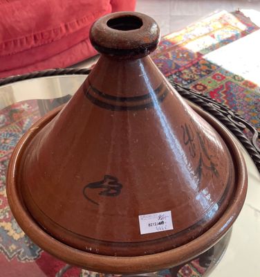 a brown vase sitting on a glass table with a red couch in the background