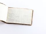 an open book on a white surface with a hand holding it