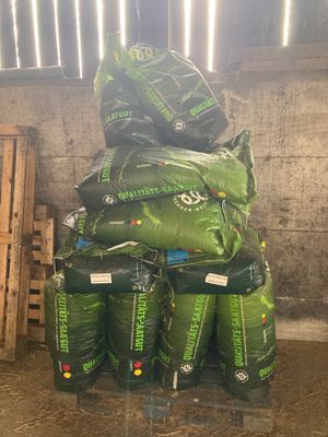 une pile de sacs remplis de matière verte posée sur une palette
