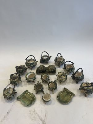 an assortment of small ceramic teapots and saucers on a table