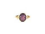 a close up of a ring with a purple stone in it