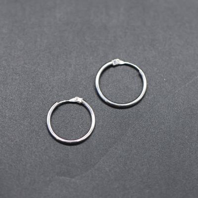 a pair of silver hoop earrings on a black surface