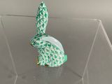 a small green and white rabbit figurine in a clear box