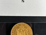 a gold coin in a glass case with a label on it