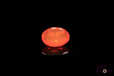 an orange diamond in the dark with a reflection on the surface