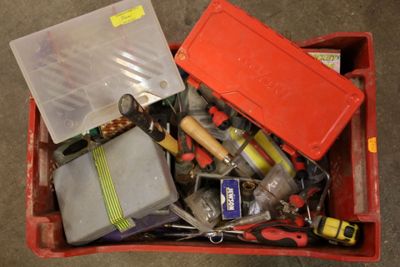 une boîte rouge posée par terre et remplie d'objets divers