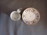a cup and saucer sitting on a table next to each other