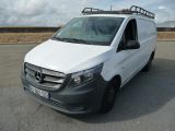 La camionnette blanche est garée sur un parking ; elle est équipée d'une galerie de toit.