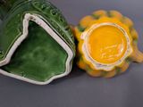 a green and yellow vase sitting next to a yellow and white vase