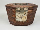 a wicker box with a metal handle on a white background