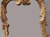 un miroir doré posé sur un socle en bois, sur fond gris