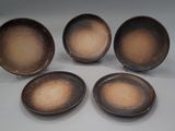 quatre assiettes marron posées les unes à côté des autres sur une table blanche