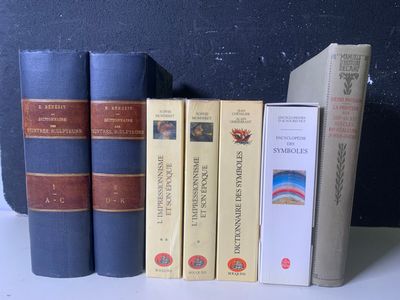 Plusieurs livres sont alignés sur une étagère devant un mur noir