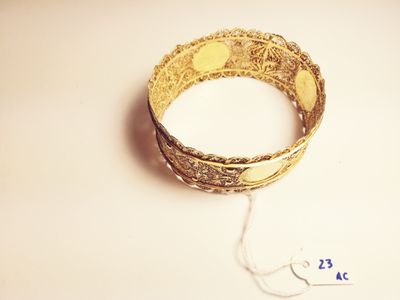 a gold bracelet that is on a white surface