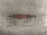 an old silver pot sitting on top of a table with writing on it