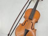 an old violin sitting on top of a white table next to a bow