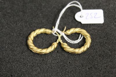 une paire de boucles d'oreilles en or sur une surface noire