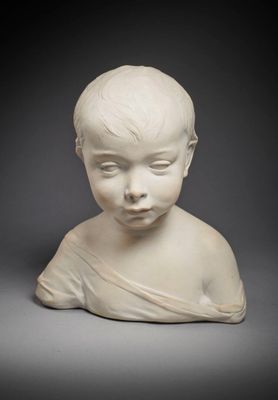 un gros plan sur la statue blanche d'un enfant posée sur une surface grise