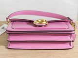 a pink purse sitting on top of a wooden table next to a tag