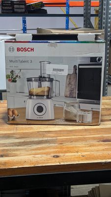 une boîte posée sur une table en bois dans un magasin, avec un appareil électroménager en arrière-plan